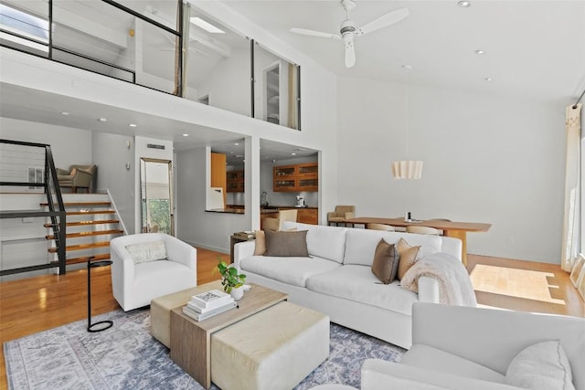 living room featuring ceiling fan, sink, a towering ceiling, and hardwood / wood-style flooring