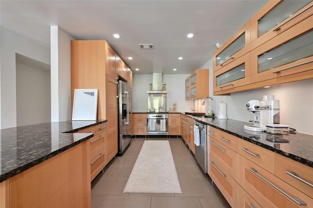 kitchen featuring light brown cabinetry, stainless steel appliances, sink, dark stone countertops, and tile patterned flooring