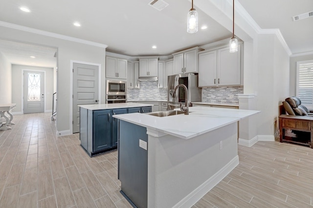 kitchen featuring sink, stainless steel appliances, hanging light fixtures, tasteful backsplash, and a kitchen island with sink