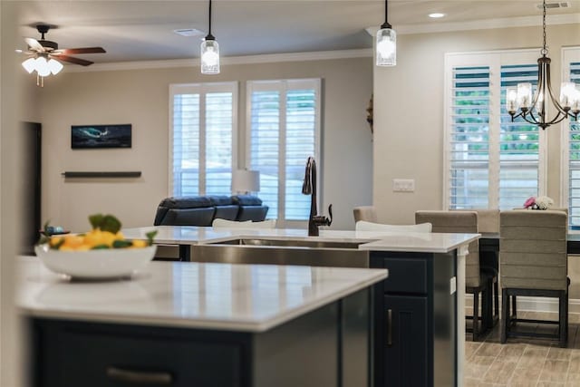 kitchen with light countertops, dark cabinets, a sink, and crown molding