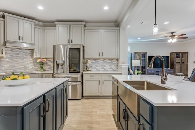 kitchen featuring an island with sink, ornamental molding, gray cabinetry, under cabinet range hood, and stainless steel refrigerator with ice dispenser