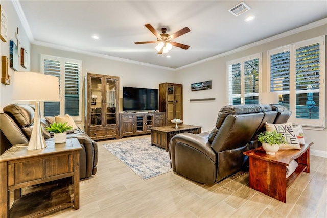 living room with ornamental molding, a wealth of natural light, visible vents, and a ceiling fan