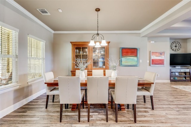 dining area featuring hardwood / wood-style floors, ornamental molding, and a notable chandelier