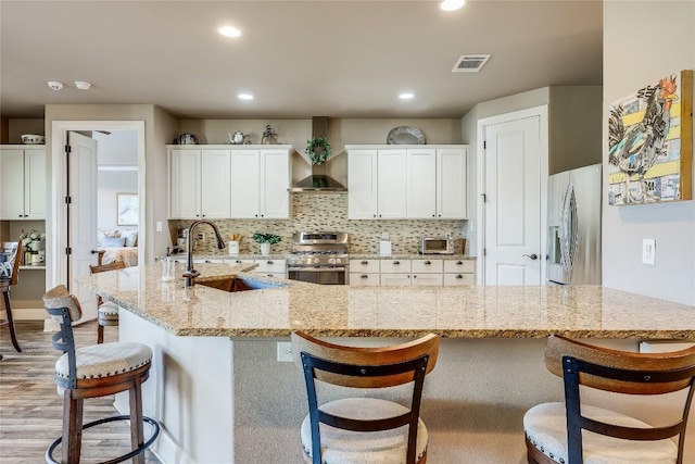 3500 Lohmans Ford Rd Unit 71, Lago Vista, TX 78645 - kitchen featuring wall chimney exhaust hood, appliances with stainless steel finishes, white cabinets, decorative backsplash, and recessed lighting