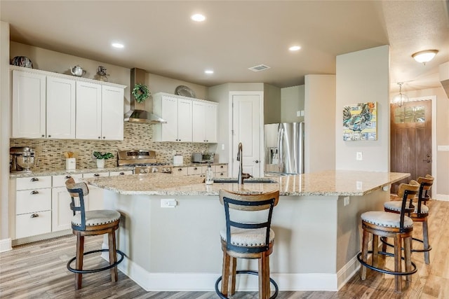 3500 Lohmans Ford Rd Unit 71, Lago Vista, TX 78645 - kitchen with stove, wall chimney range hood, stainless steel fridge, light wood-type flooring, and a breakfast bar area