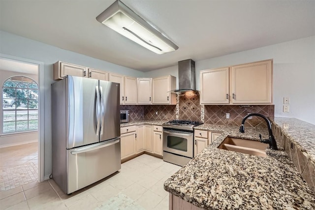 kitchen with appliances with stainless steel finishes, light stone counters, wall chimney exhaust hood, and sink