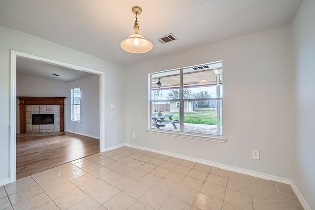 empty room with light tile patterned floors and a tiled fireplace