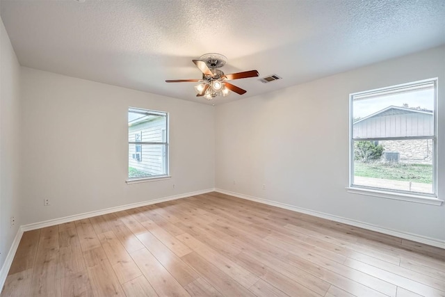 unfurnished room featuring a textured ceiling, light hardwood / wood-style flooring, ceiling fan, and a healthy amount of sunlight