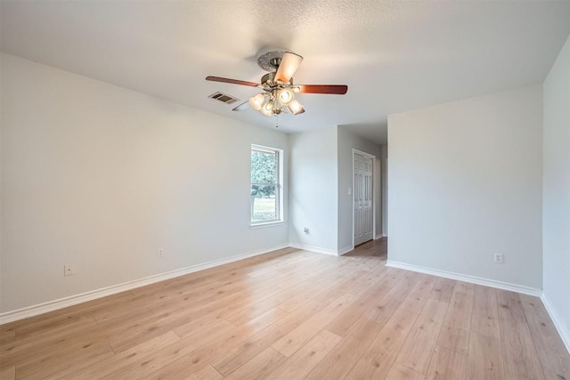 empty room featuring a textured ceiling, light wood-type flooring, and ceiling fan