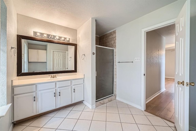 bathroom featuring tile patterned flooring, vanity, a textured ceiling, and walk in shower