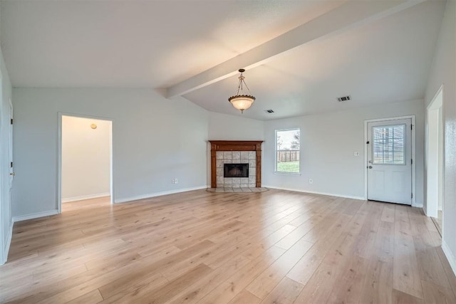 unfurnished living room with vaulted ceiling with beams, a tile fireplace, and light hardwood / wood-style flooring