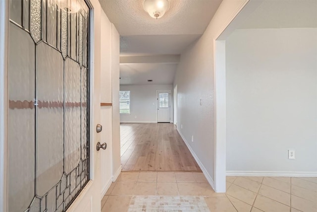 hallway with light tile patterned floors and a textured ceiling