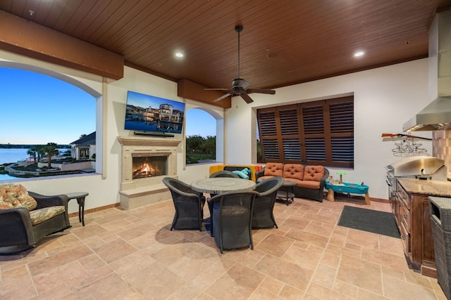 view of patio / terrace featuring an outdoor living space with a fireplace, grilling area, a water view, and ceiling fan