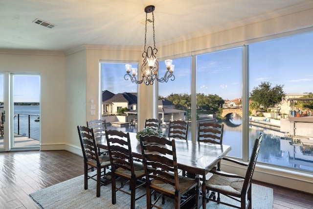 dining area with a water view, crown molding, plenty of natural light, and a notable chandelier