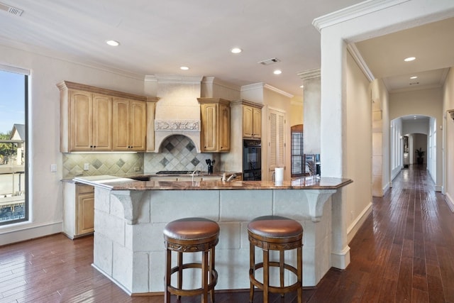 kitchen with tasteful backsplash, kitchen peninsula, light brown cabinetry, and ornamental molding