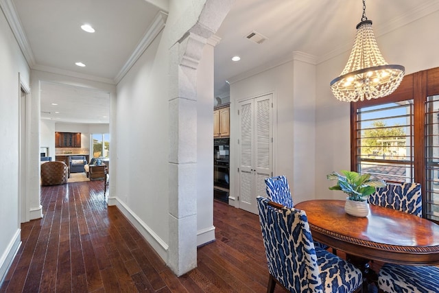 dining area featuring an inviting chandelier, dark wood-type flooring, and ornamental molding