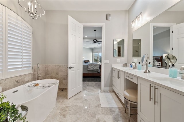 bathroom featuring vanity, a bath, and ceiling fan with notable chandelier