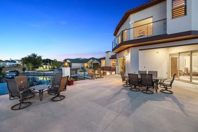 patio terrace at dusk featuring a balcony