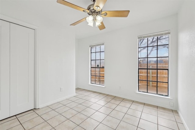 spare room featuring ceiling fan, light tile patterned floors, and a healthy amount of sunlight