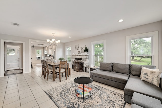 tiled living room with a brick fireplace, plenty of natural light, and a notable chandelier