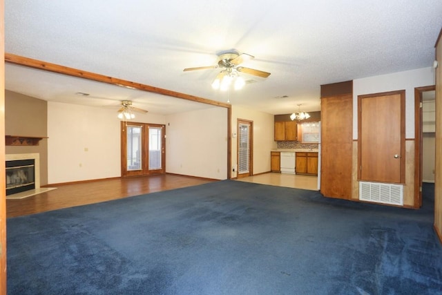 unfurnished living room with carpet flooring, beamed ceiling, and ceiling fan with notable chandelier