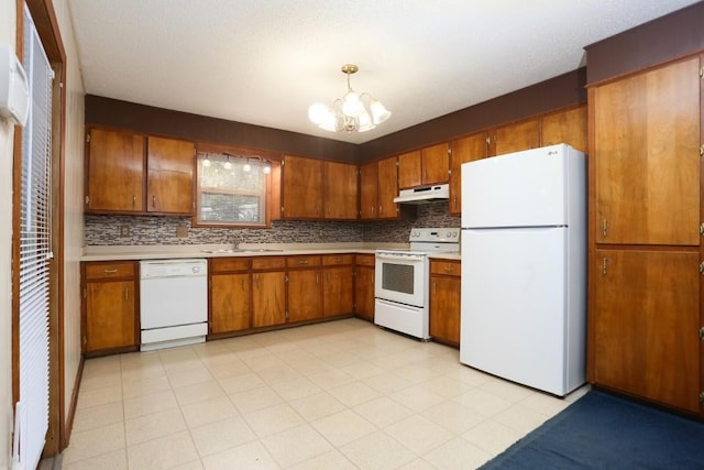 kitchen with pendant lighting, white appliances, backsplash, sink, and a notable chandelier