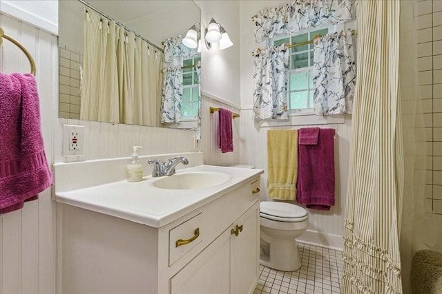 bathroom with wooden walls, tile patterned flooring, vanity, and toilet