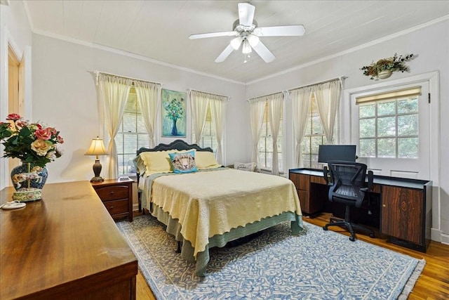 bedroom with multiple windows, wood-type flooring, ceiling fan, and crown molding