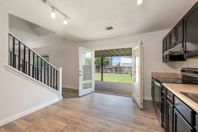 kitchen with stainless steel electric range, light hardwood / wood-style floors, dark brown cabinetry, and track lighting