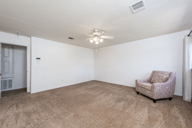 living area featuring ceiling fan, carpet floors, and a textured ceiling