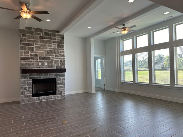 unfurnished living room featuring a stone fireplace and ceiling fan