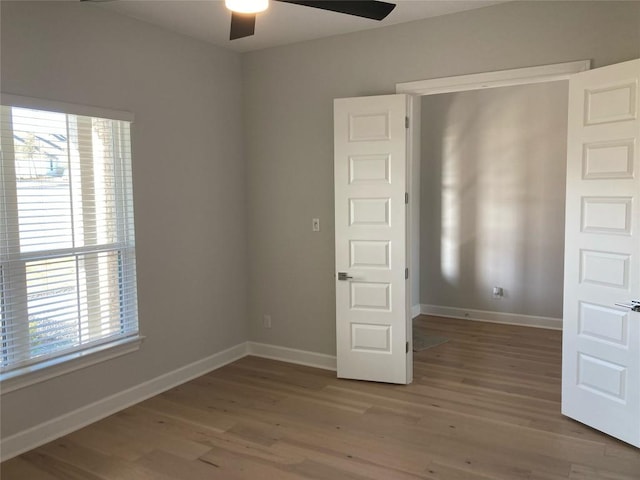 unfurnished bedroom featuring multiple windows, hardwood / wood-style flooring, and ceiling fan