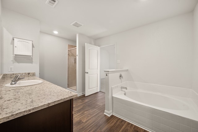 bathroom with plus walk in shower, wood-type flooring, and vanity