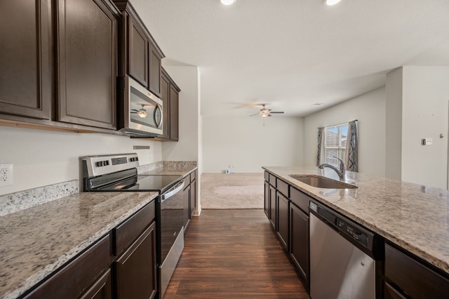 14405 Boomtown Way, Elgin, TX 78621 - kitchen featuring appliances with stainless steel finishes, dark wood-style flooring, dark brown cabinetry, light stone countertops, and a ceiling fan