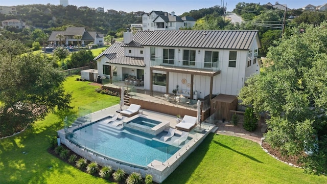 rear view of house featuring a yard, an outdoor living space, a balcony, and an in ground hot tub