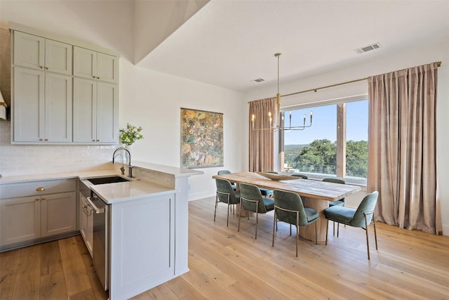 kitchen with kitchen peninsula, sink, hanging light fixtures, and stainless steel dishwasher