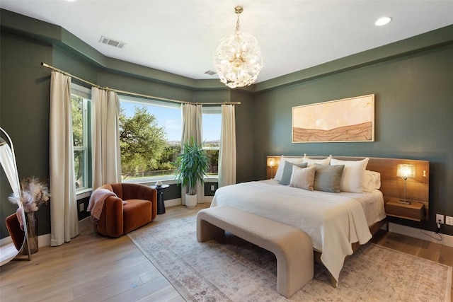 bedroom featuring an inviting chandelier, multiple windows, and light hardwood / wood-style flooring