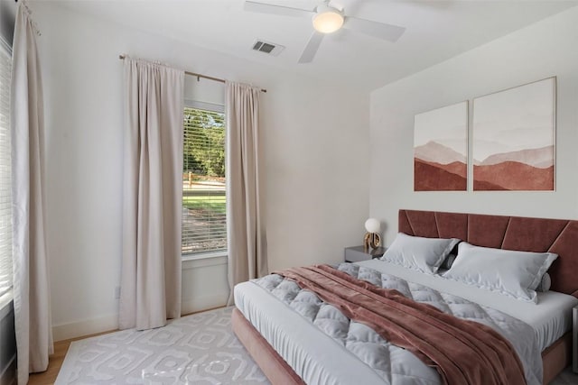 bedroom featuring ceiling fan, light hardwood / wood-style flooring, and multiple windows