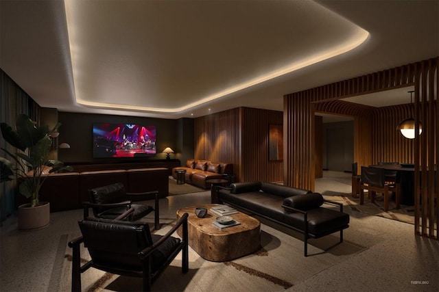 home theater featuring a tray ceiling and wooden walls