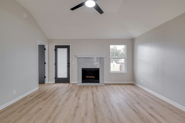 unfurnished living room with light wood-type flooring, vaulted ceiling, ceiling fan, and a tiled fireplace