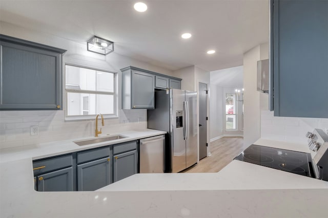 kitchen with stainless steel appliances, plenty of natural light, light hardwood / wood-style floors, and sink