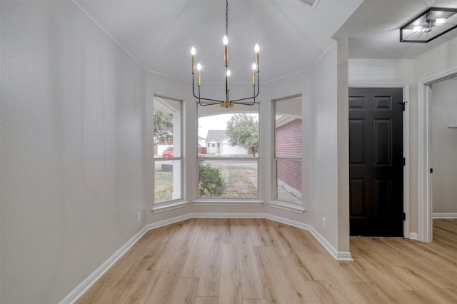 unfurnished dining area featuring light wood-type flooring and an inviting chandelier