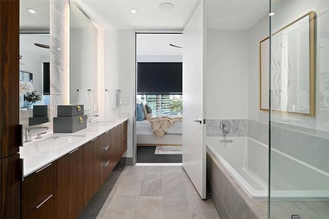 bathroom with tile patterned flooring, a relaxing tiled tub, and vanity