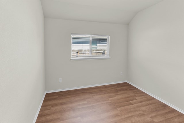 spare room featuring vaulted ceiling and light hardwood / wood-style flooring