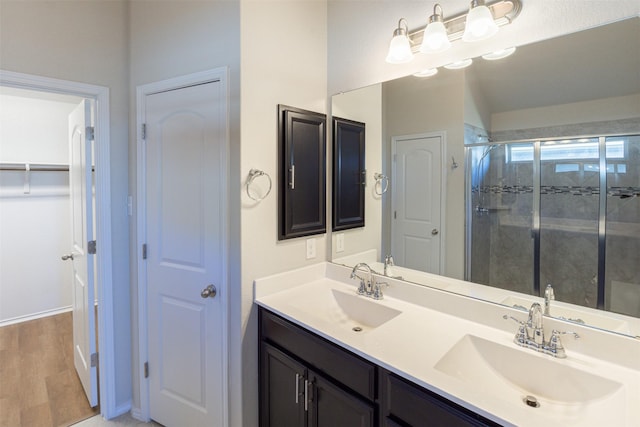 bathroom with hardwood / wood-style flooring, vanity, and a shower with door