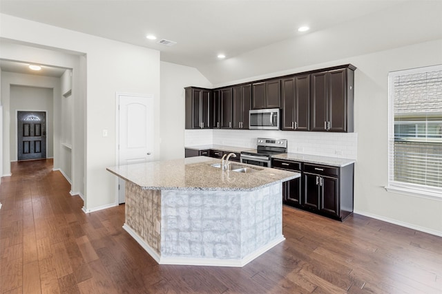 kitchen featuring a kitchen island with sink, light stone countertops, sink, and appliances with stainless steel finishes