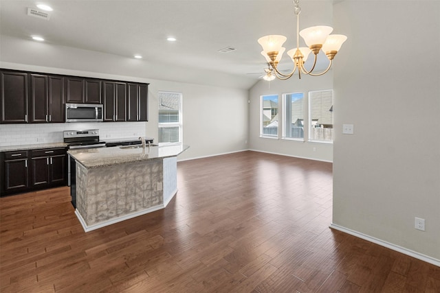 kitchen featuring a kitchen island with sink, hanging light fixtures, decorative backsplash, light stone countertops, and appliances with stainless steel finishes