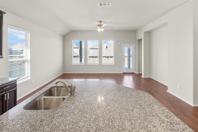 kitchen with light stone countertops, ceiling fan, dark wood-type flooring, and sink