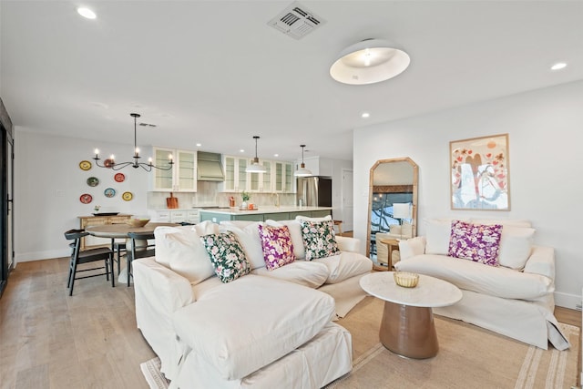 living room with an inviting chandelier and light wood-type flooring