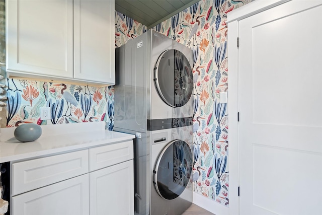 laundry room with cabinets and stacked washer / drying machine